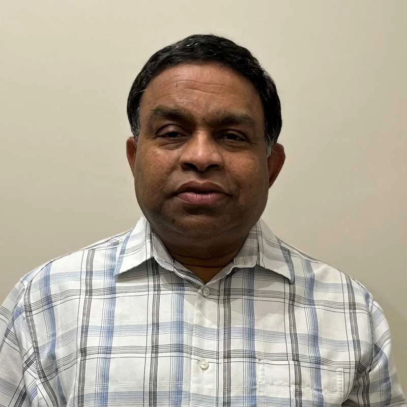 Portrait of a man in a white and blue plaid shirt looking at the camera.