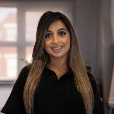 Woman with long brown and blonde hair, smiling. Wearing a black shirt.