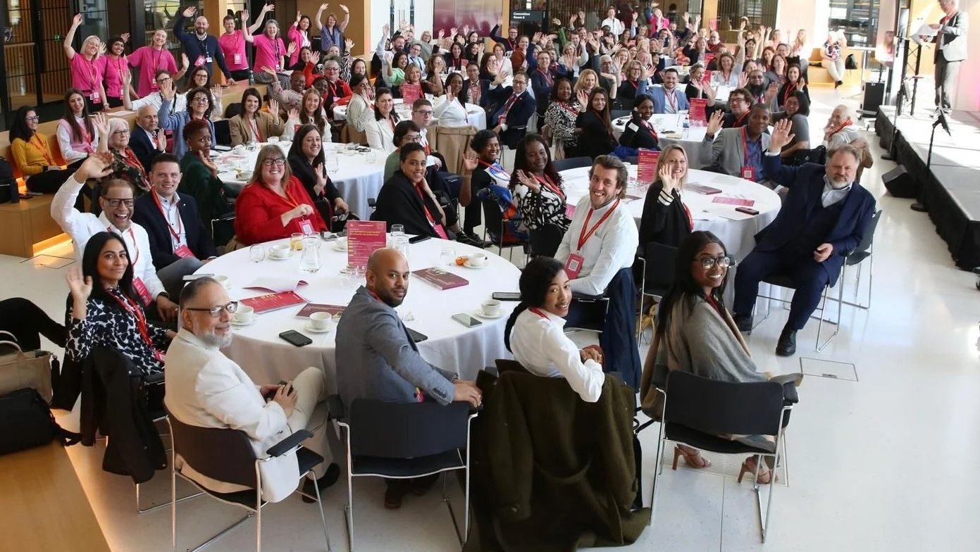 Large group of people at an event, many waving.