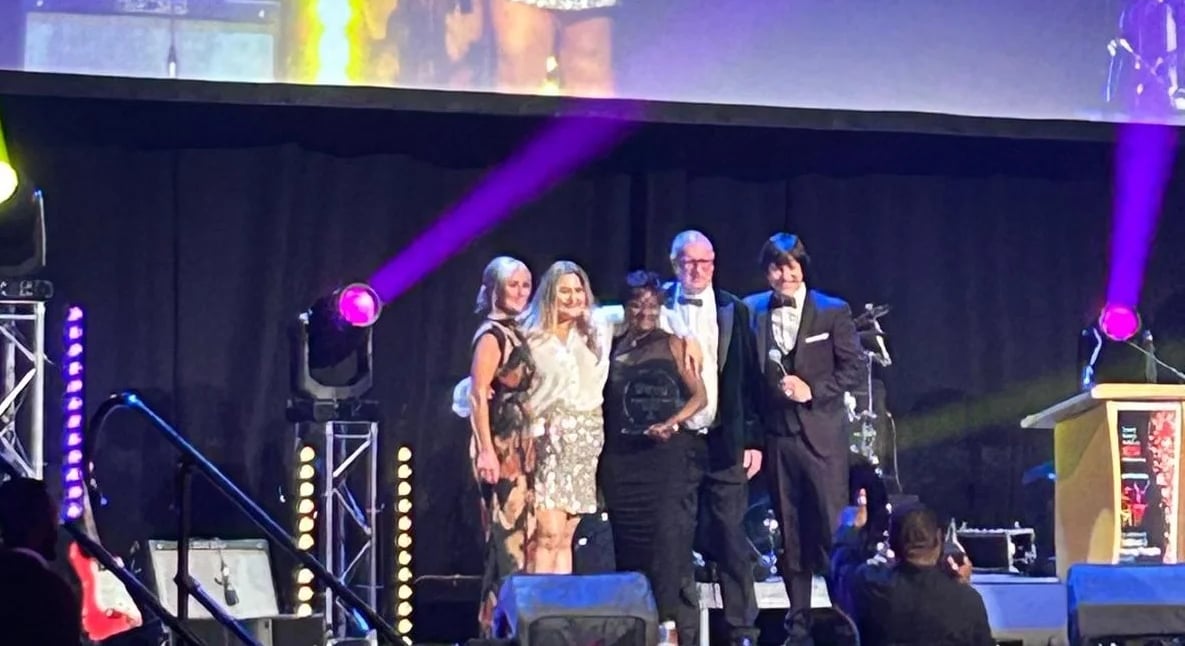 People on stage with awards, at a gala.